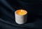 Decorative scented candle burns against black fabric