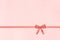 Decorative shiny ribbon with bow on pastel pink background with copy space for text, coral toned Top view, Template
