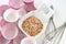 Decorative sugar colored stars in two white bowls, whipping rods and paper cupcake bases on white background