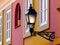Decorative vintage style street light on wrought iron wall bracket with colorful stucco house facades beyond