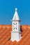 Decorative white chimney on orange house roof