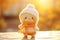 Decorative winter-themed knitted figurine. Cute knitted character in kawaii hat on sunny background