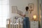 Decorator hanging pictures on wall in baby room. Interior