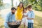 Dedicated father helping son to use wooden tongs during family picnic