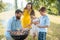 Dedicated father helping son to use wooden tongs during family picnic