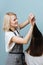 Dedicated hairdresser woman trimming client`s hair ends over blue