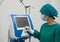 A dedicated healthcare professional in a sterile surgical gown maneuvers a high-tech machine, the latest in medical advancements,