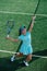 Dedicated teenage girl training on a tennis court, throwing ball up and serving