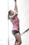 Dedicated woman climbing rope in crossfit gym