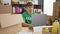 Dedicated young hispanic man concentrates as he sits at the table, volunteering, working online on his laptop at a bustling