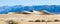 Deep blue mountains form a backdrop to panoramic sand dunes at Mesquite Flat