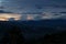 Deep blue sunset in tropical landscape with colorful orange, pink, yellow clouds on blue sky over dark blue valley with hazy hills