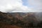 The deep, colorful gorge of Waimea Canyon with red dirt mountains and vegetation growing on the slopes on an overcase day