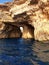 Deep dark blue sea with glassy waves and the rough limestone rocks of Malta islands