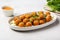 Deep fried cheese balls with sauce on white plate in bright kitchen. Generative AI