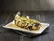 Deep-fried Marble Goby fish in Siam Style served in a dish isolated on wooden board side view dark background