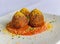 Deep fried salmon cake balls on top of red sauce, sprinkled with grated ginger and chives.