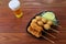 Deep-fried skewered onion ,pork and quail eggs on the black crockery on the wooden table