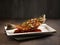 Deep-fried Star Grouper in Sweet and Sour Sauce served in a dish side view on dark background