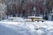A deep, heavy layer of untouched, fresh, fluffy white snow covers picnic tables and benches in Gauja National Park, mid