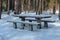 A deep, heavy layer of untouched, fresh, fluffy white snow covers picnic tables and benches in Gauja National Park, mid