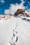 Deep marks in white snow. Snow tops and clouds amid blue skies. Winter mountain travel concept