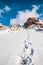 Deep marks in white snow. Snow tops and clouds amid blue skies. Winter mountain travel concept