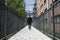 Deep perspective of a man walking between fences towards a hospital.