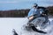 In deep powder snowdrift snowmobile rider driving fast