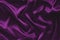 Deep, rich, purple colored satin. Folded and flowing background. Decoration design. Soft focus. Luxury fashion concept