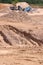 Deep track at the bottom of a quarry with a sorting machine and a heap of large pebbles in the background, August 2021