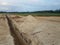 Deep trench cut in the dirt at construction site