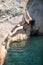 Deep water soloing, young female rock climber on cliff