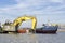 Deepening the water area of the port. A floating excavator loads soil onto a barge