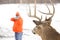 Deer hunter taking aim at a whitetail deer