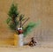 Deer made of cones and twigs decorated with bells on jute reel with green pine branches and cone on homespun cloth. Handmade.