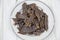 Deer meat Lat. Cervidae dried, cut into strips on a round plate with a wooden table background. Food is a delicacy snack