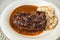 Deer meat steak, plum spicy sauce, dumpling on plate, on white table, closeup