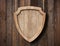 Defense protection shield shaped sign made of bright wood and hanging on ropes with wood planks background