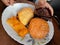 Deferent variety of snacks display on a plate a hand is holding chocolate muffin