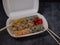 Defferent type of rolls or sushi set in a white plastic take-away box with chopsticks on gray stone table