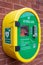 A defibrillator or AED in a secure case on a brick wall in the street