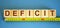 Deficit word on cubes arranged behind the ruler on blue background