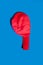 A deflated red balloon on a blue background