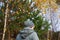 Defocus back view of young woman in striped hat walking in yellow and green autumn forest. Natural fall background