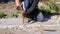 Defocus bricklayer removing irregularities on floor screed with hammer and chisel. Male hands in red work gloves smash