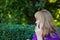Defocus caucasian blond woman talking on the phone outside, outdoor. 40s years old woman in purple blouse in park
