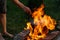 Defocus close up of human hand holding fire flame. Man cooking fish soup in the iron bowler over a campfire. Soup in a