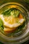 Defocus close-up slice lemon and leaves of mint in glass jug of lemonade natural green background. Pitcher of cool