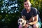 Defocus close-up young caucasian man smiling and seating with dog. The portrait of a guy squatting near the siberian